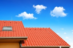 Roof house with tiled roof on blue sky.